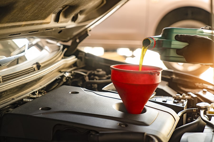 mechanic adding new oil to car at oil change franchise